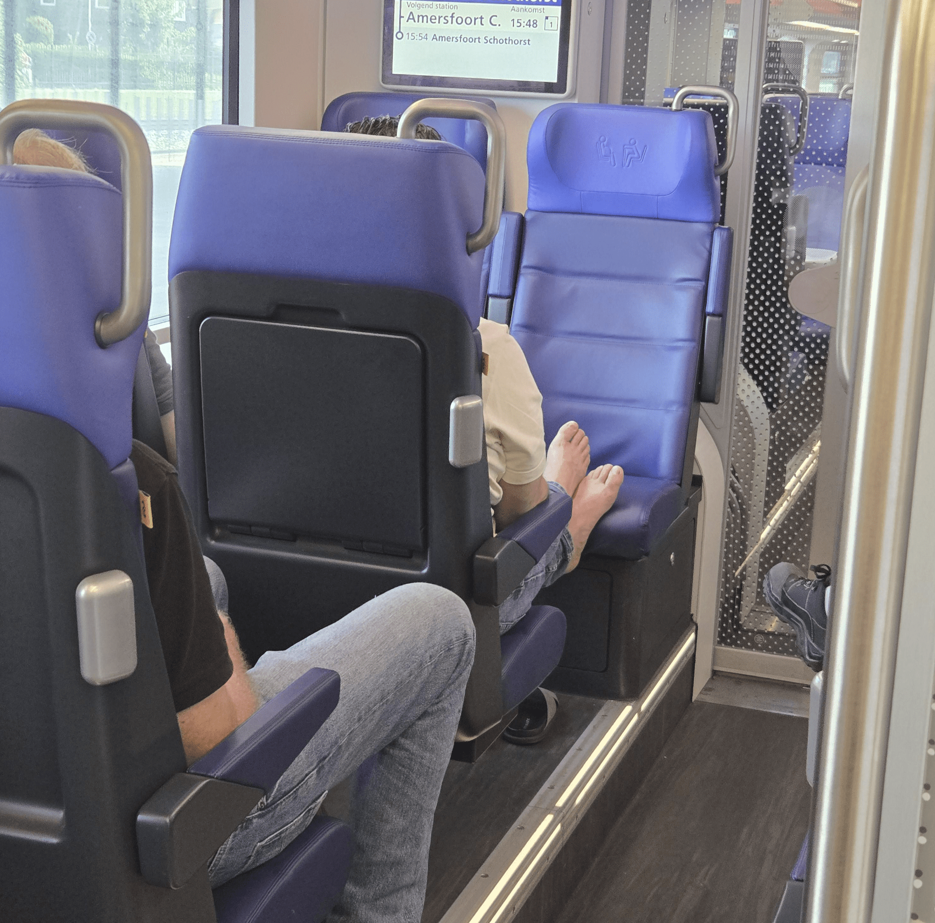 man met voeten op stoel van de trein